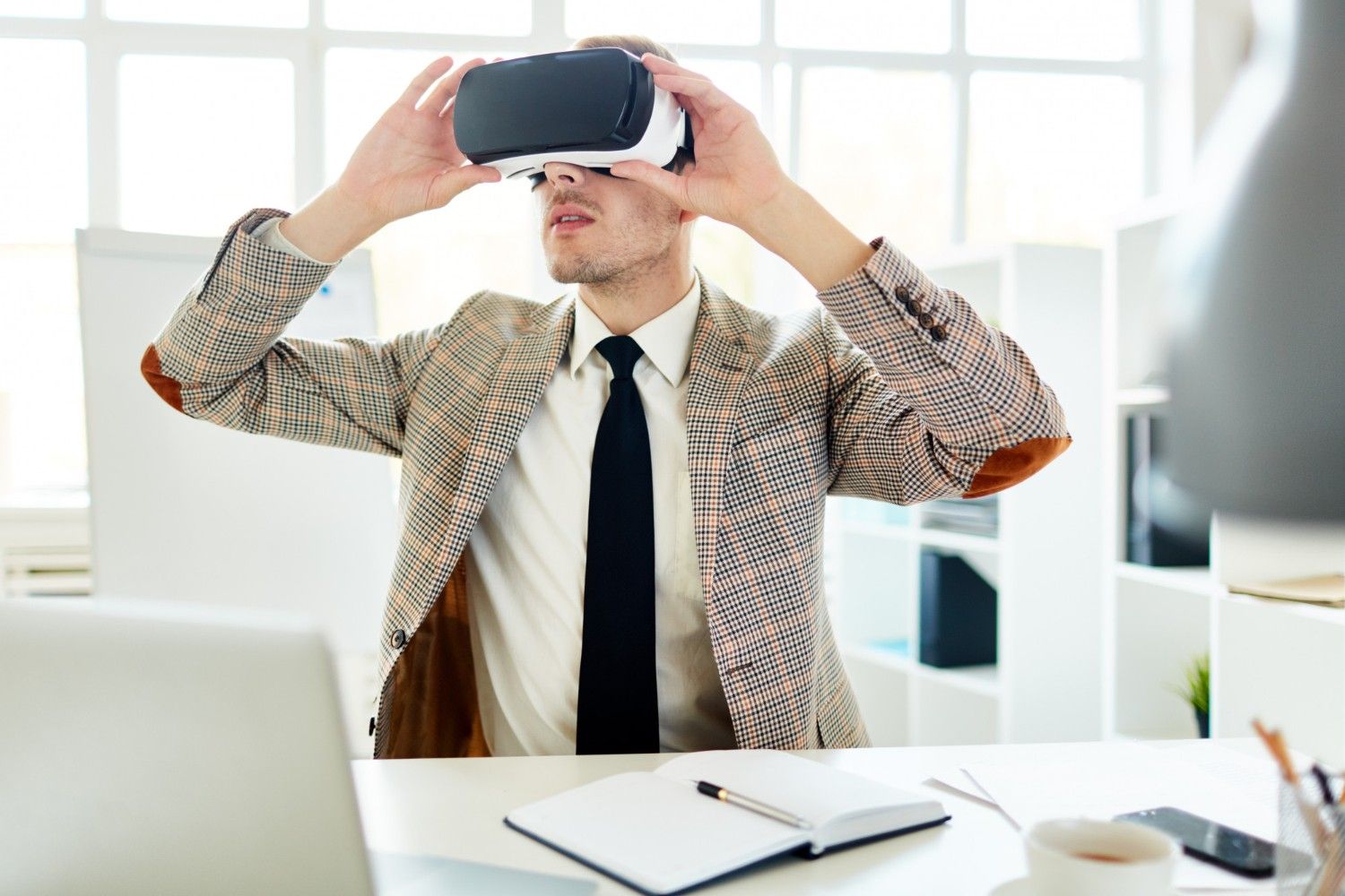 Businessman wearing a VR headset at his office desk