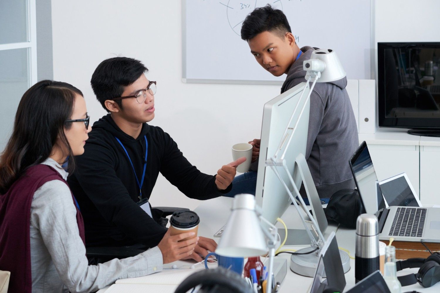 Young professionals collaborating and discussing work around a computer monitor